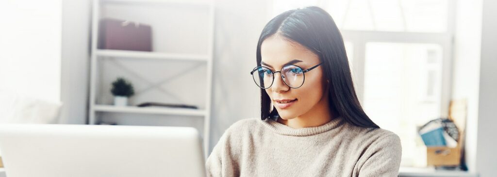 Young woman with glasses looking at laptop
